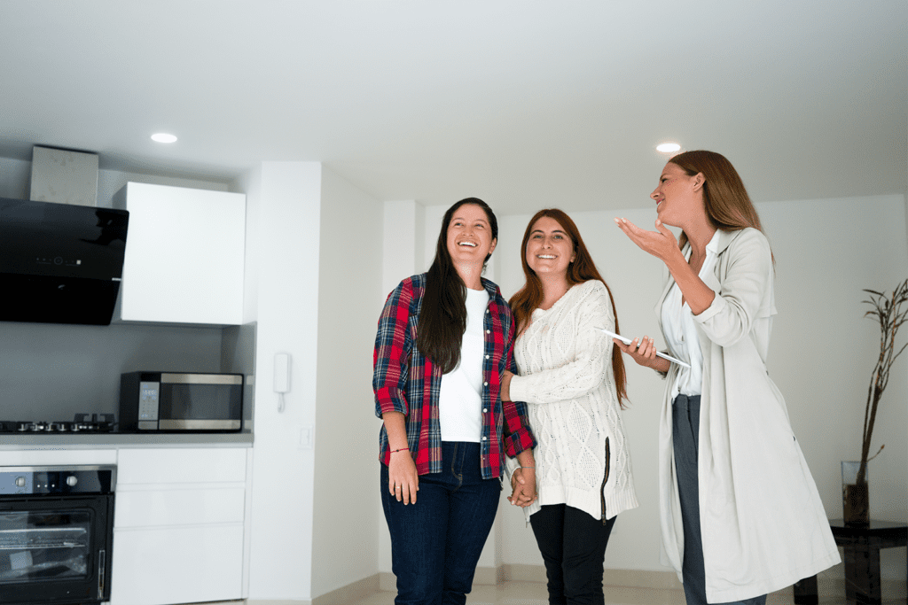 A couple and real estate agent stand in an open kitchen at a house showing